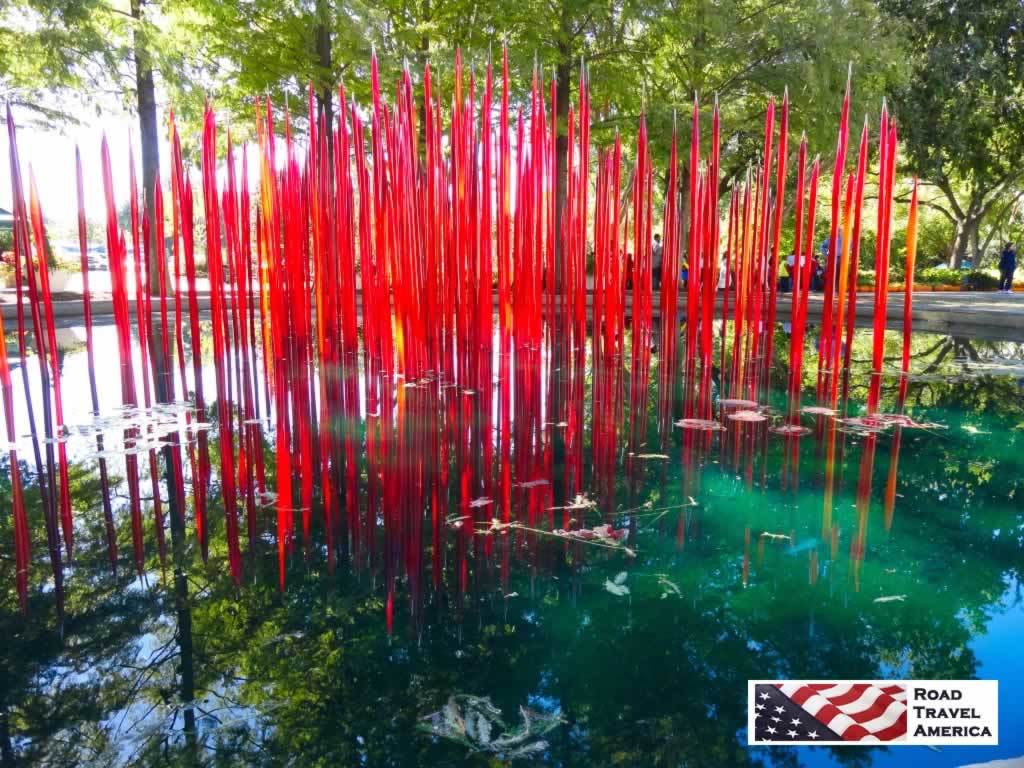 Spires of red in a green pond at the Dallas Arboretum during the Dale Chihuly Exhibit in 2012