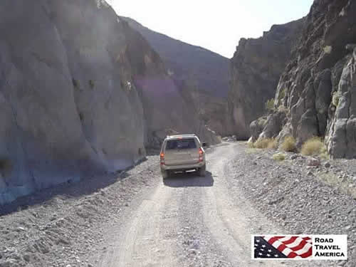 Driving the narrow passage between towering rocks in Titus Canyon Road in Death Valley National Park